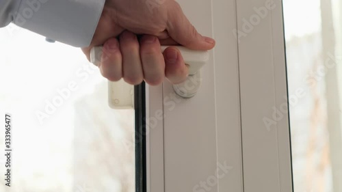 A man opens a window to ventilate the room. Close up.