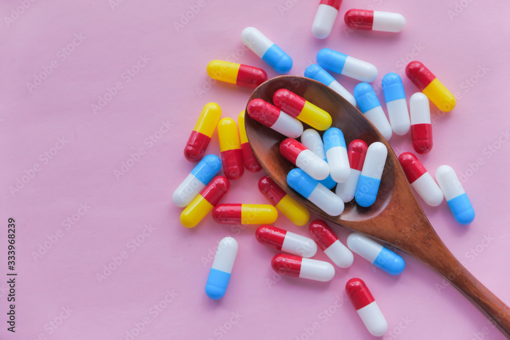 Close up of colorful pills on spoon on pink background Close up of colorful pills on spoon on pink background