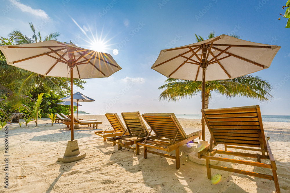 Beach beds and umbrellas on a tropical island. family vacation or summer holiday, beach landscape and shoreline, sunny weather, exotic destination.