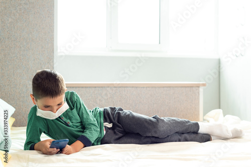 Stay at home quarantine coronavirus pandemic prevention. A child from boredom plays at home on the phone during quarantine. Prevention epidemic. COVID-19.