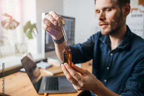 Vitamins and supplements. Hand holding pipette of Hemp oil. Close up man uses CBD oil. Medical cannabis. Healthy lifestyle photo