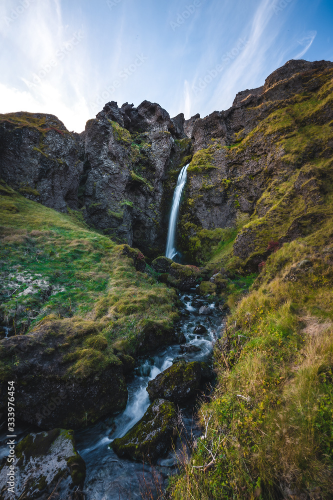 Image of Beautiful Waterfall in Iceland with unique rough landscape taken during bright sunny weather