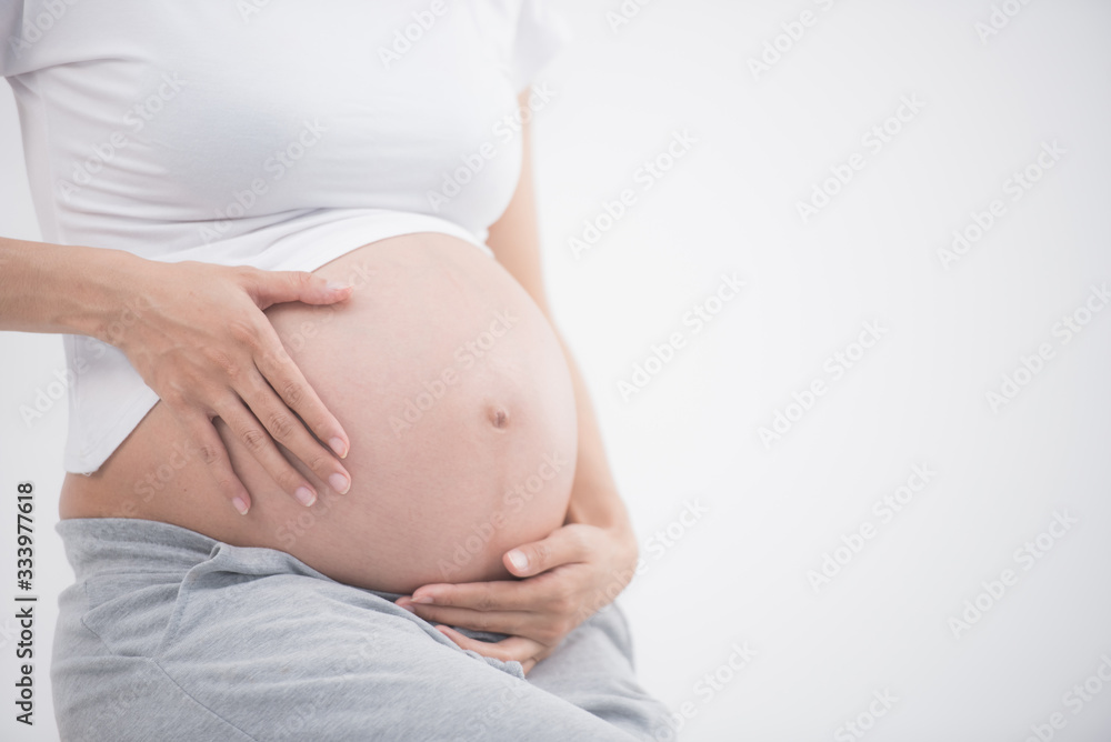 beautiful pregnant woman feeling happy at home while taking care of her child. the young expecting mother holding baby in pregnant belly. healthy. maternity prenatal care and woman pregnancy concept beautiful pregnant woman feeling happy at home while taking care of her child. the young expecting mother holding baby in pregnant belly. healthy. maternity prenatal care and woman pregnancy concept