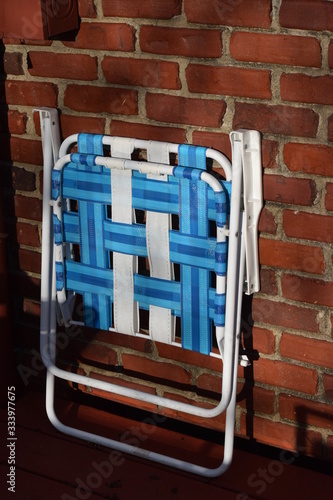 Folded Lawn Chair Against a Brick Wall