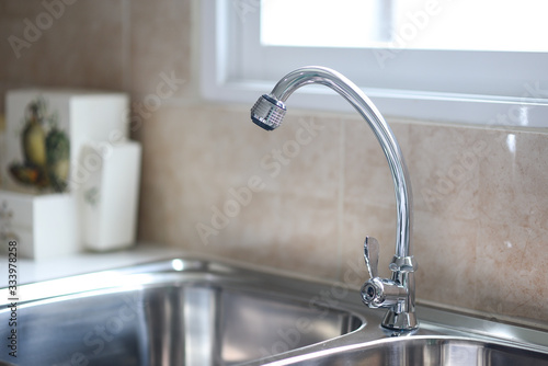 Sink in the kitchen and the sun shines through the windows.