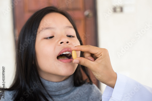 cute little girl having sick and happy to taking medicine in mouth. .Kid having pharmaceutical medical dose for pain relief or antibiotic medication curing from illness. healthcare,medicine concept .
