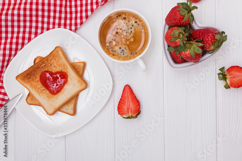 Toasted bread and jam in heart shape, strawberries and coffee