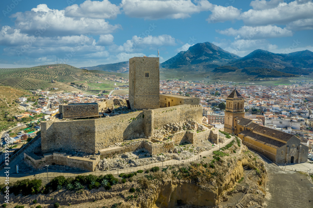 Aerial view of medieval Alcaudete castle in Andalusia Spain with donjon, high stone walls and loopholes next to the town church