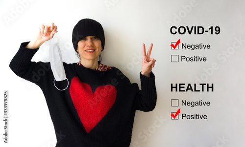 Young beaufitul woman removing her mask because she beat Corona virus, isolated on white background. She won illness war, happiness concept. Female making / showing victory v-sign. photo