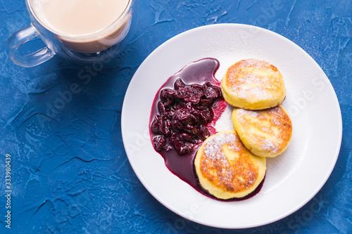 Breakfast and delicious concept - Pancakes from cottage cheese with jam, blue background, top view