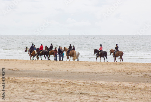 riders on horses on the beach close to North sea