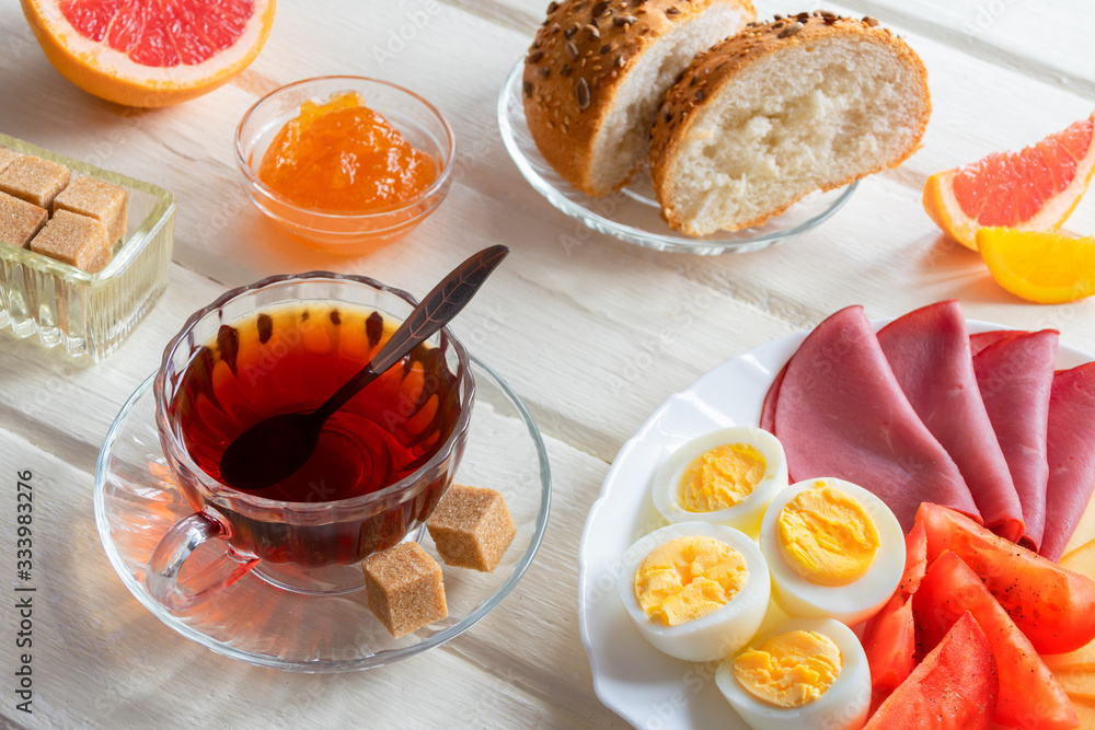 Fresh delicious breakfast with soft boiled egg, cheese, ham fresh bread and cup coffee or tea on light wooden background. Fresh delicious breakfast with soft boiled egg, cheese, ham fresh bread and cup coffee or tea on light wooden background.