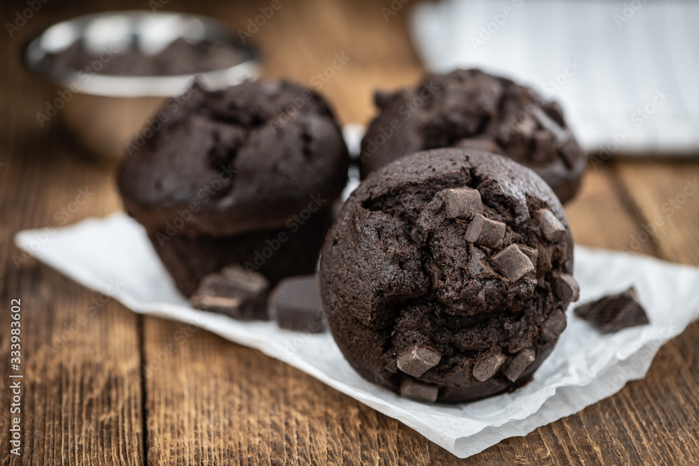 Fototapeta premium Old wooden table with fresh Chocolate Muffins (close-up shot; selective focus)