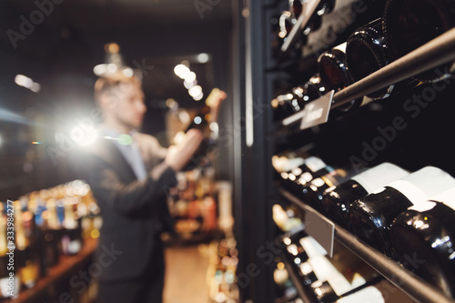 Bartender sommelier takes bottle of red wine from counter of restaurant drinks store