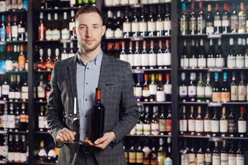 Sommelier man holds bottle red wine and glass on dark background restaurant