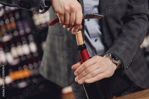 Opening wine bottle with corks crew on dark background restaurant