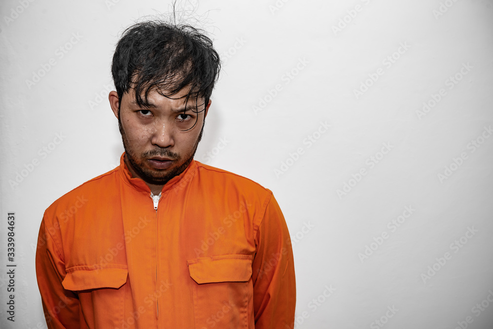 Obraz premium Prisoner in orange robe concept,Portrait of asian handsome man in Prison uniforms,Bandit has a lot of muscle,