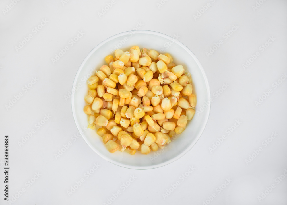 Delicious and fresh yellow sweet corn seed gathered in a white cup over a white background Delicious and fresh yellow sweet corn seed gathered in a white cup over a white background