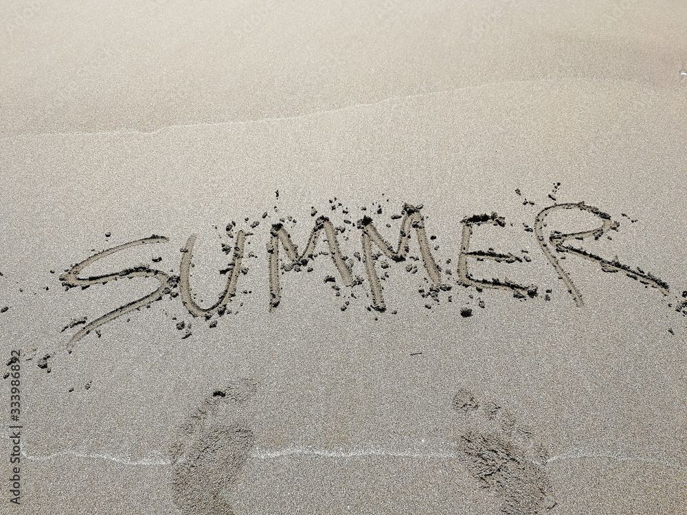 Fototapeta premium The inscription Summer on the sand of the beach and footprints. the concept of leisure holiday