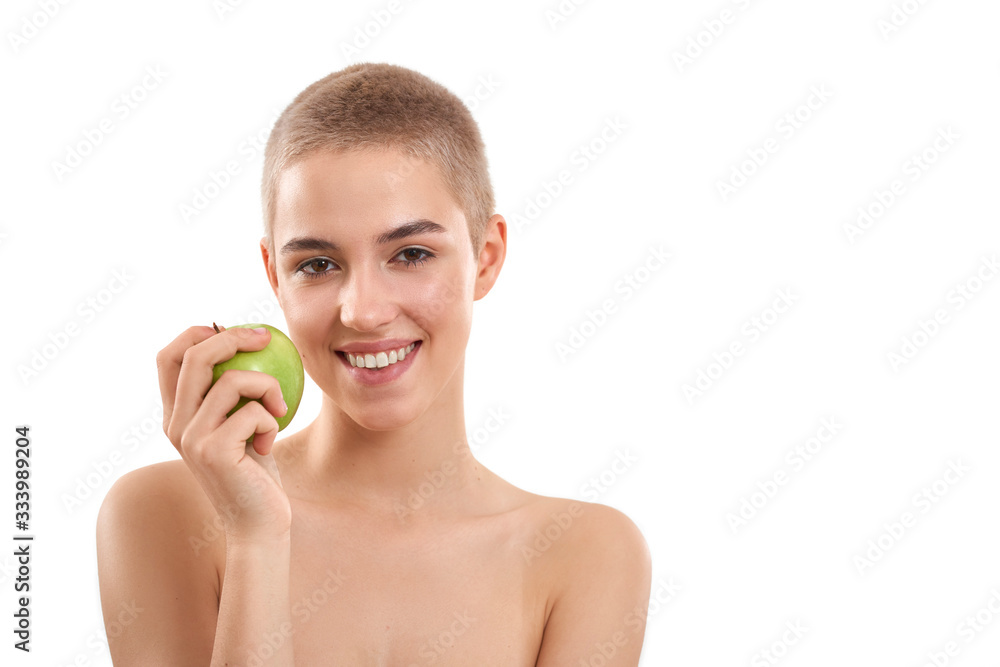 Healthy lifestyle. Portrait of young and happy attractive blonde woman with short haircut holding a fresh apple and smiling while standing against white background Healthy lifestyle. Portrait of young and happy attractive blonde woman with short haircut holding a fresh apple and smiling while standing against white background