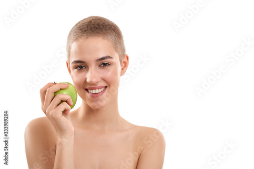 Healthy lifestyle. Portrait of young and happy attractive blonde woman with short haircut holding a fresh apple and smiling while standing against white background