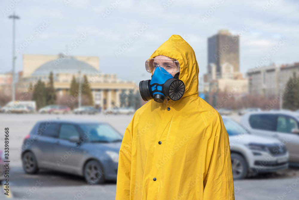 Virologist in a protective yellow suit and a respirator on the streets of the city. The doctor is wearing goggles, gloves, and a mask. Virologist in a protective yellow suit and a respirator on the streets of the city. The doctor is wearing goggles, gloves, and a mask.