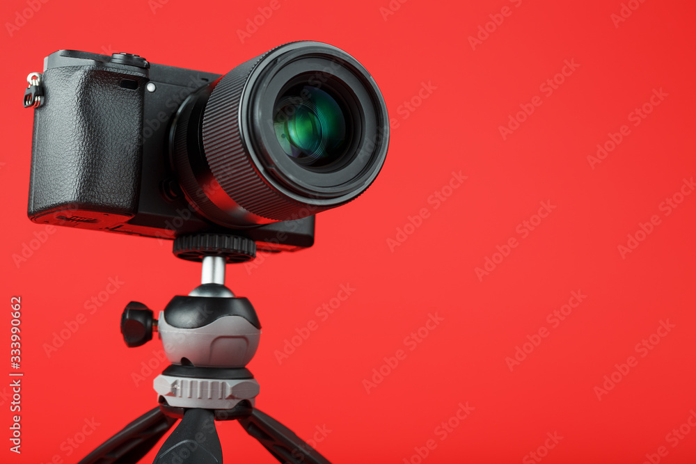 Professional camera on a tripod, on a red background. Record videos and photos for your blog, reportage