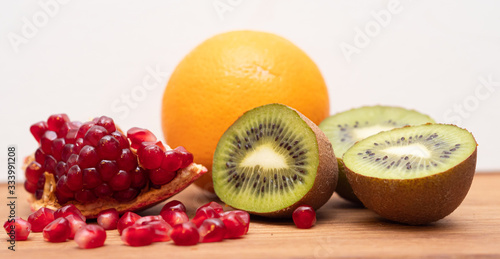 Kiwi orange and pomegranate on a wooden table