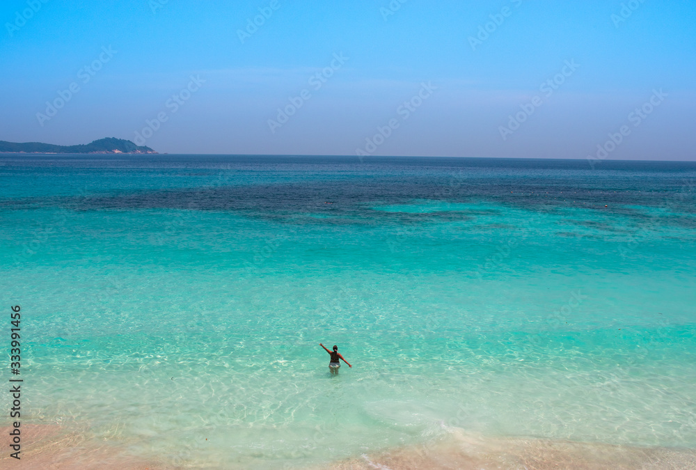 mujer en playa paradisiaca de malasia (Perhentian) mirando al horizonte