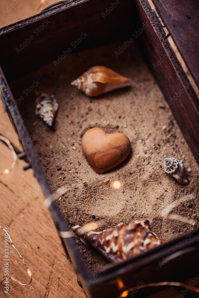 Liebe, Schatz, Schatztruhe Herz aus Holz in Sand mit Muscheln in