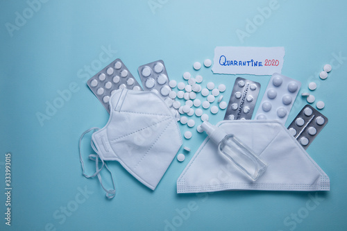 Quarantine 2020 phrase text on a blue background with pills, sanitizer and protective masks