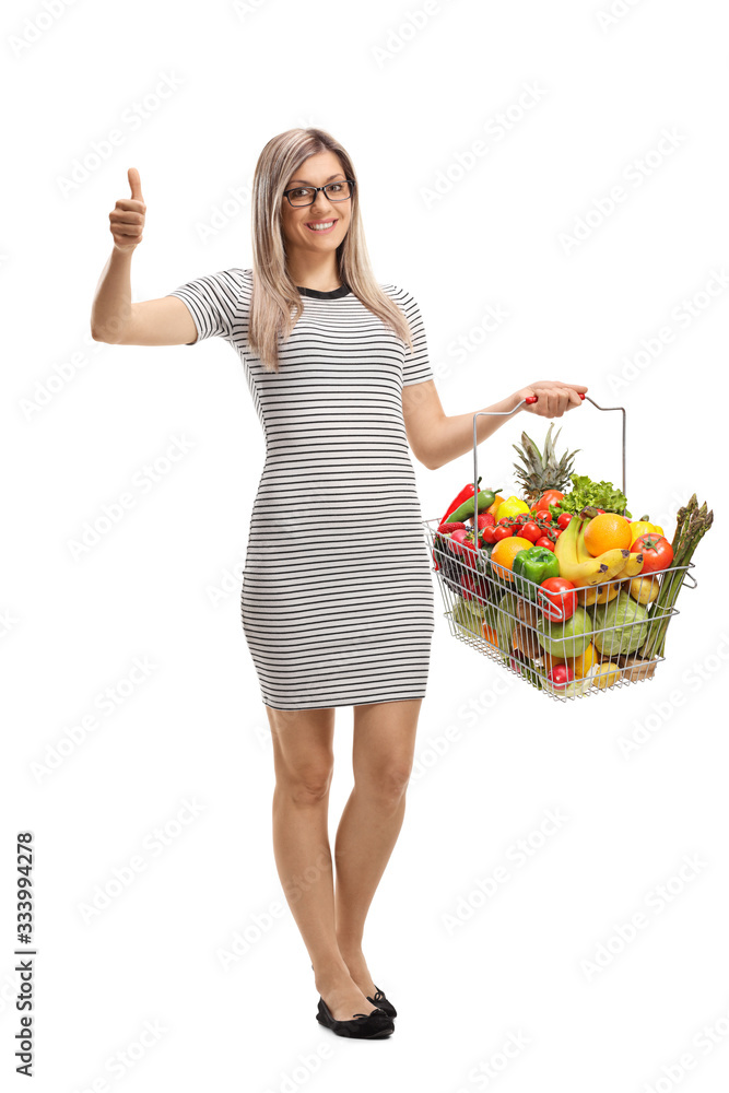 Young woman with a shopping basket with fruits and vegetables showing thumbs up Young woman with a shopping basket with fruits and vegetables showing thumbs up