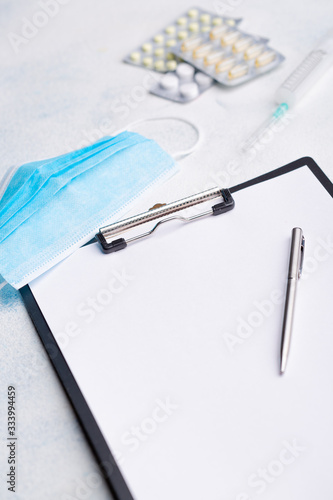 Medical face shield  disposable syringe  pills  pen and paper on white background. The concept of protecting health from the virus