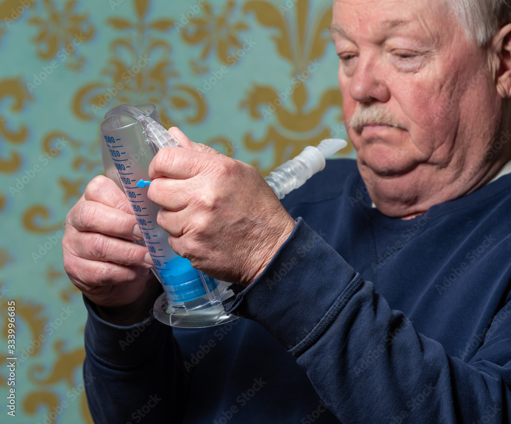 Elderly man using incentive spirometer for breath improvement. Helpful