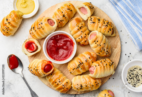 Photography Homemade sausages in pastry with ketchup and mustard on a wooden board