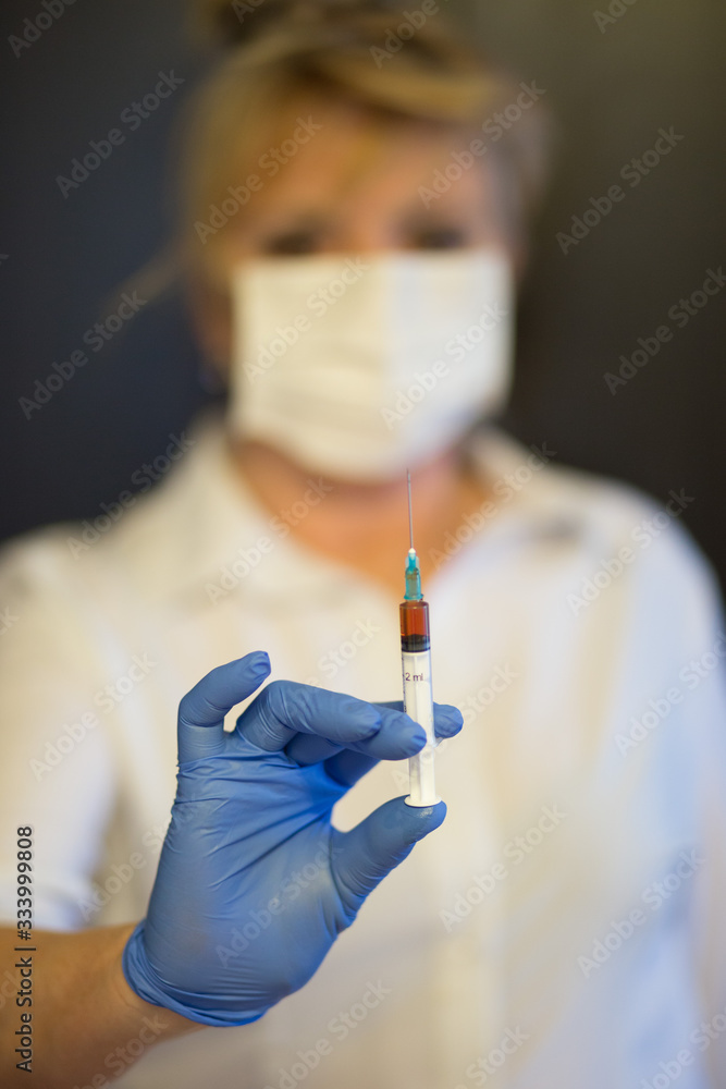 Senior woman wearing mask, gloves holds a syringe in hand. Selective focus. epidemic virus symptoms. Senior woman wearing mask, gloves holds a syringe in hand. Selective focus. epidemic virus symptoms.