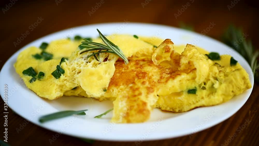 hot fried omelet with chopped green onions in a plate on a wooden table hot fried omelet with chopped green onions in a plate on a wooden table