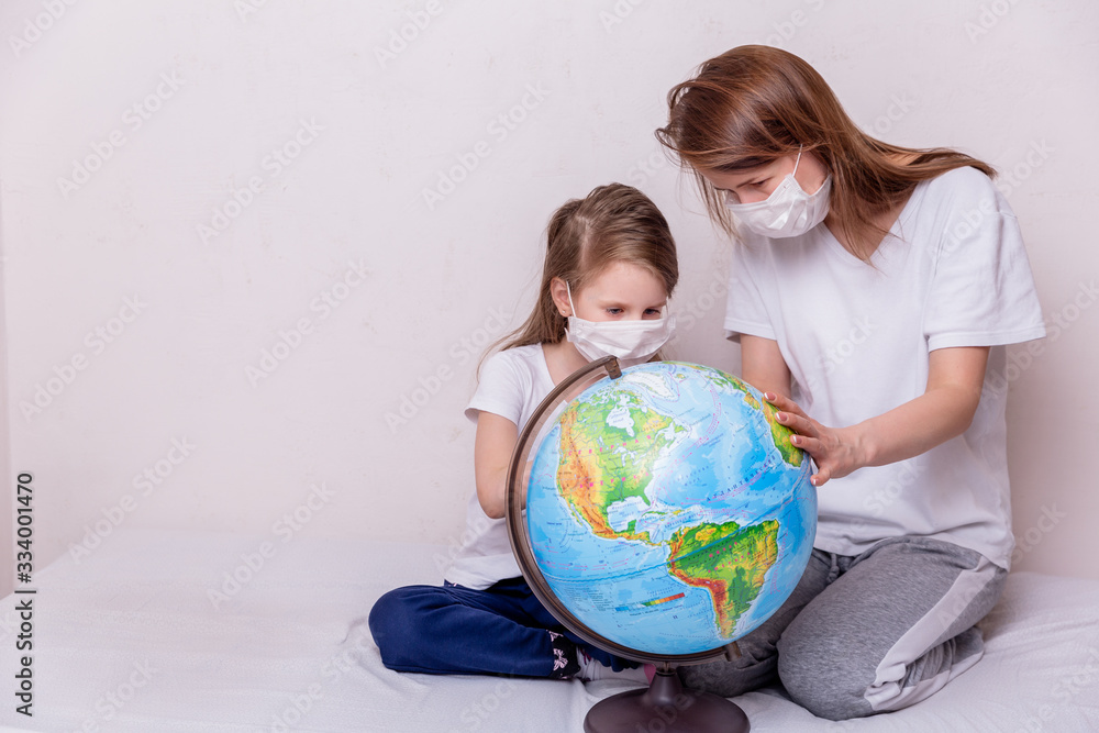 The concept of coronavirus quarantine. Young woman and her daughter in medical masks in isolation at home. The idea of a global virus. Theme of health and medicine. Free space for text The concept of coronavirus quarantine. Young woman and her daughter in medical masks in isolation at home. The idea of a global virus. Theme of health and medicine. Free space for text