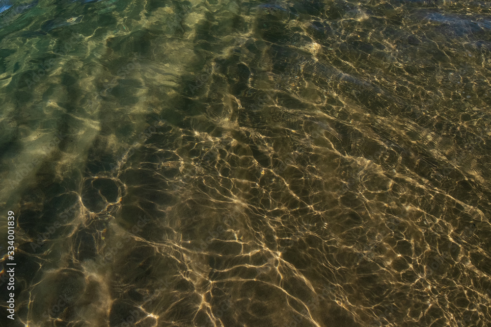 Water on the beach. Waves and sand. The sun glare from the water on the sand. 