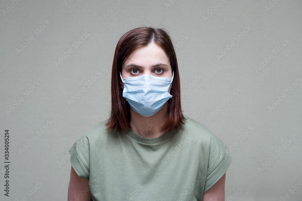 Corona virus. Young woman in a face mask on a grey background. Protection against infection, virus, dust Corona virus. Young woman in a face mask on a grey background. Protection against infection, virus, dust