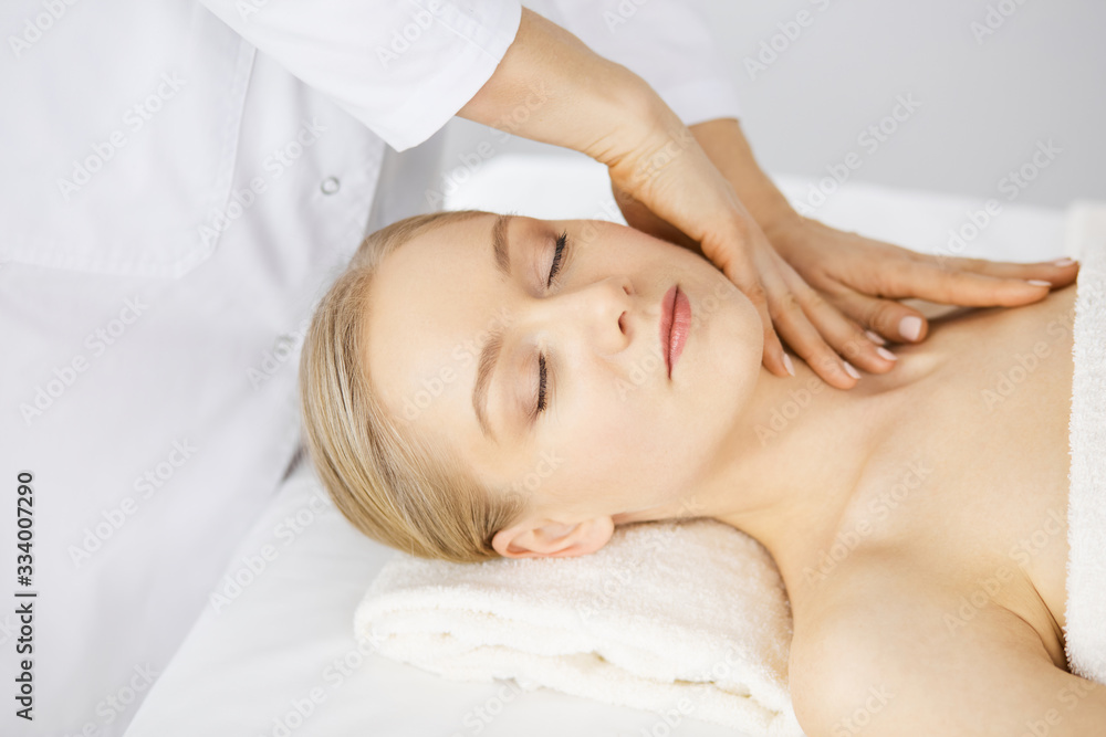 Beautiful caucasian woman enjoying facial massage with closed eyes in spa salon. Relaxing treatment in medicine and Beauty concept Beautiful caucasian woman enjoying facial massage with closed eyes in spa salon. Relaxing treatment in medicine and Beauty concept