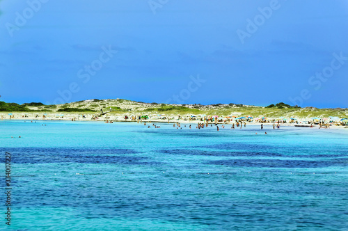 Turquoise sea and people on sandy beach at Formentera  Spain.