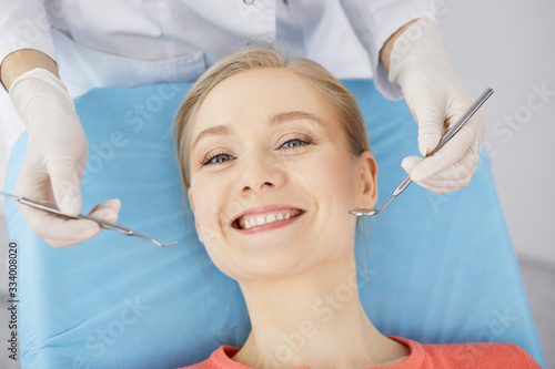 Smiling caucasian woman is being examined by dentist at dental clinic. Healthy teeth and medicine, stomatology concept