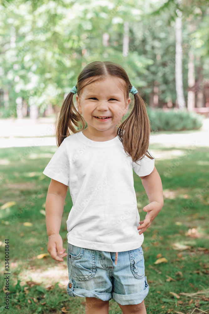 Cute smiling little girl 5 years old in white t-shirt in park Cute smiling little girl 5 years old in white t-shirt in park