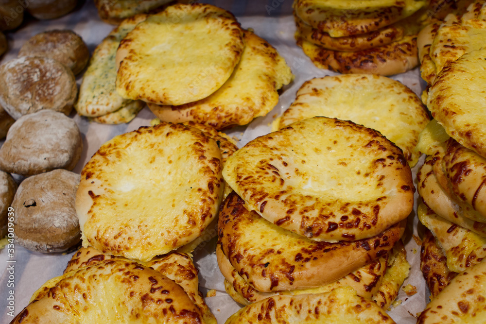 large flat cheese buns with grated cheese on top on a bakery counter