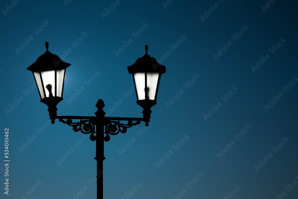 Street lamp with lamps in a classic style against a dark blue sky. Dark evening or night.