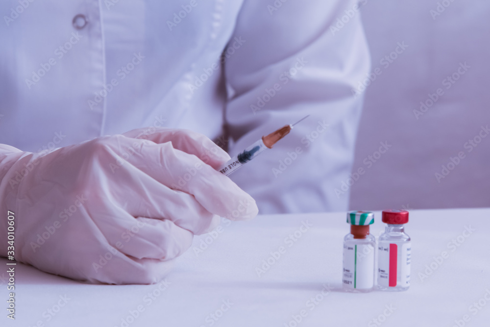 The coronavirus vaccine is ready for use. The doctor's gloved hand grabs the syringe. On the table in front of the doctor are vials of vaccine. The coronavirus vaccine is ready for use. The doctor's gloved hand grabs the syringe. On the table in front of the doctor are vials of vaccine.