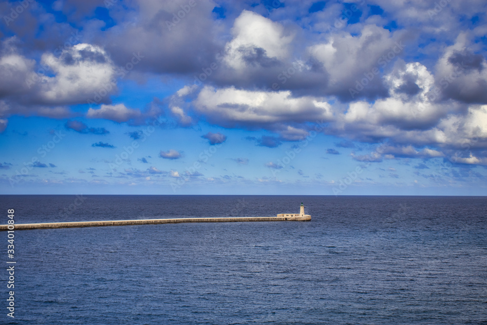 Lighthouse in the blue sea with clouds formation, nice sea view with lighthouse in Malta, way to the lighthouse from the new Grand Harbour Bridge in Valletta, Valletta lighthouse,Malta