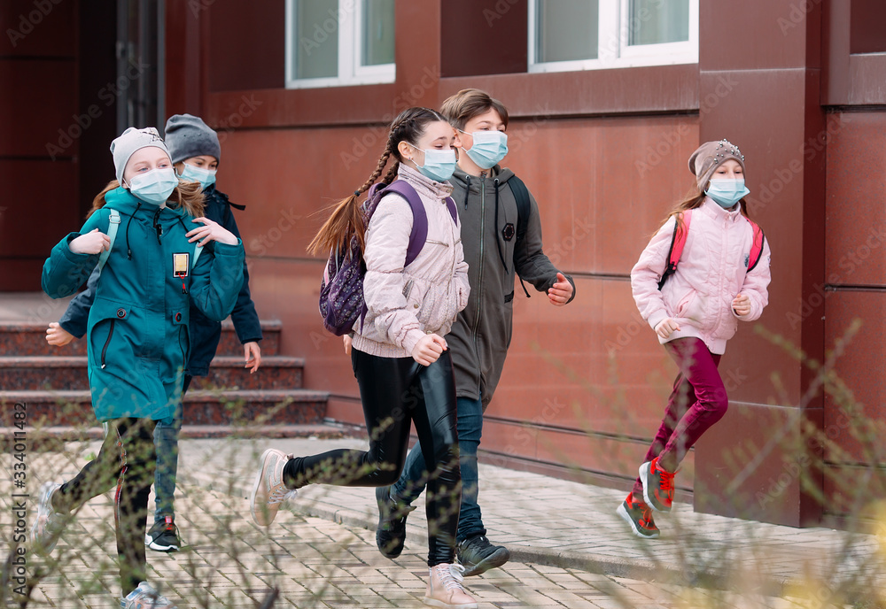 Children students in medical masks leave the school. - obrazy, fototapety, plakaty 