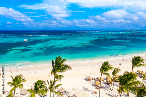 Aerial drone view of beautiful caribbean tropical beach with straw umbrellas, palms and boats. Bavaro, Punta Cana, Dominican Republic. Vacation background.